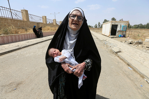 An elderly displaced Iraqi woman who fled from Islamic State militants carries a baby in Mosul
