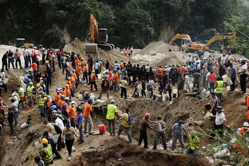 Rescue team members and volunteers remove dirt with buckets from the site of a mudslide in Santa Catarina Pinula