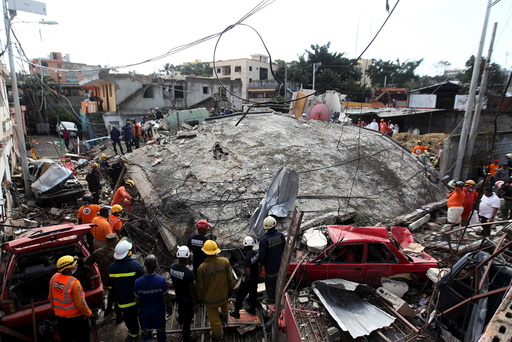 Emergency services workers search a house that collapsed after explosions at an LPG gas distribution station in Santo Domingo, Dominican Republic