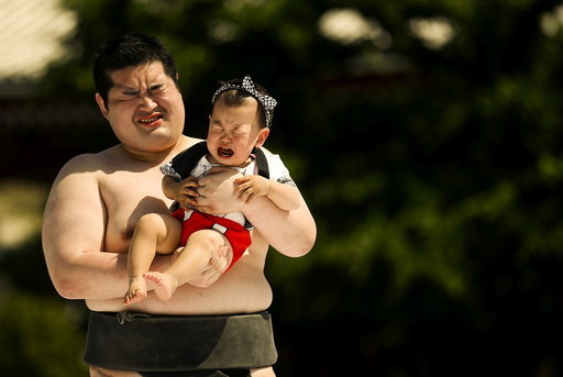 Amateur sumo wrestler holds baby during baby crying contest at Sensoji temple in Tokyo