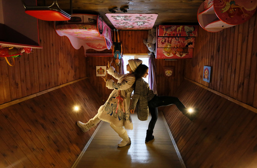 A visitor and an employee dressed as Snegurochka pose for a picture inside an upside down house at the Royev Ruchey Park of Flora and Fauna in the suburbs of Krasnoyarsk