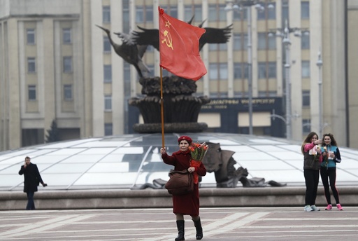A communist woman walks with a communist flag and flowers in the center of in Minsk to celebrate the International Women's Day