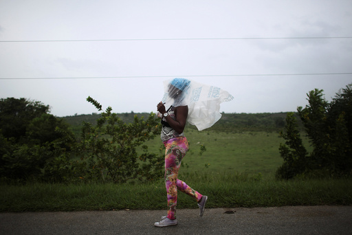 Naomi Rivera, 41, shields herself from the rain ahead of the arrival of Hurricane Matthew in Guantanamo, Cuba