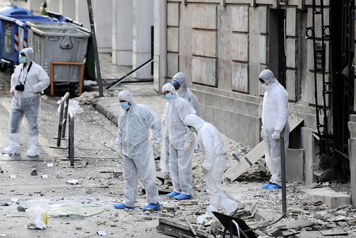 Forensic experts search for evidence on a street where a bomb exploded outside the entrance of the Hellenic Business Federation offices in Athens