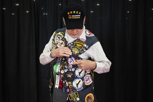 NRA lifetime member Lee Smith, 79, from Houston, shows off his pins and patches to event attendees while taking part in the National Rifle Association's annual meeting in Houston, Texas