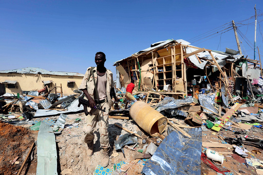 A Somali government soldier walks past the scene of a suicide bomb explosion at the Wadajir market in Madina district of Somalia's capital Mogadishu