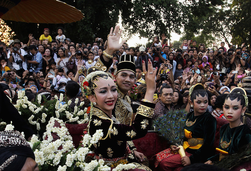 KPH Yudanegara and his wife GKR Bendara wave to the crowd in a horse-drawn carriage in Yogyakarta