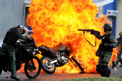 Riot security forces clash with demonstrators as a motorcycle is set on fire during a protest against Venezuelan President Nicolas Maduro's government in San Cristobal