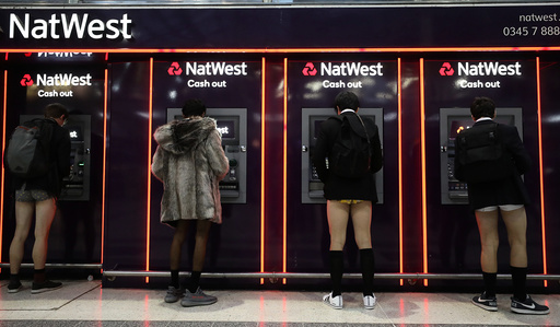 Passengers without trousers stand at cash machines as part of the 'No Trousers on the Tube Day' event, in London