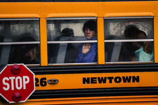 Children look out through condensation in the windows of school bus number 26 as it pulls into Newtown High School in Newtown, Connecticut