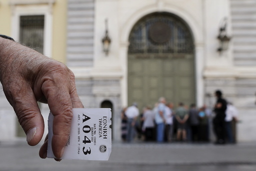 A pensioner holds his priority ticket as he waits to receive part of his pension at a National Bank branch in Athens, Greece