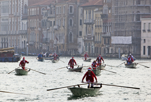 People dressed as Santa Claus ride their gondolas in the Venice lagoon