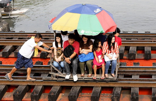 Commuters ride on a trolley along a railroad track in Manila, Philippines