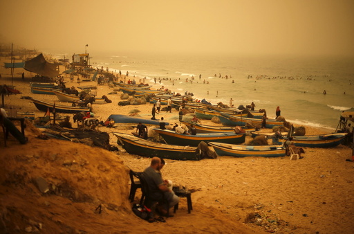 Palestinians sit on a beach along the Mediterranean Sea during a sandstorm in the northern Gaza Strip