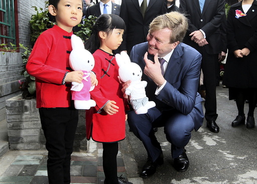 Netherlands' King Willem-Alexander gestures to a girl as he visits a hutong, or small alley, at the Qianmen area in Beijing