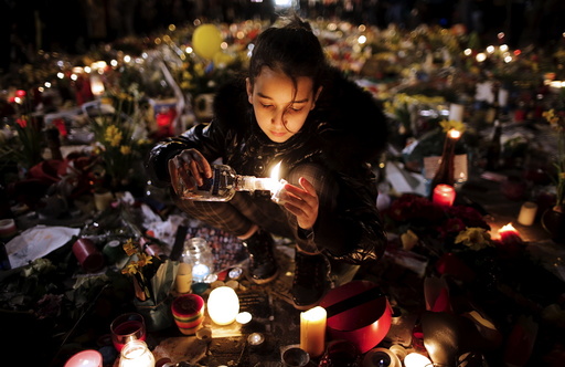 A girl lights candles as people pay tribute to the victims of Tuesday's bomb attacks, at the Place de la Bourse in Brussels, Belgium