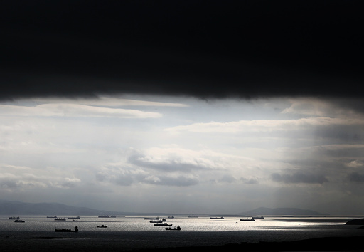 Cargo ships are seen sailing under storm clouds at open sea near the port of Piraeus, in Athens