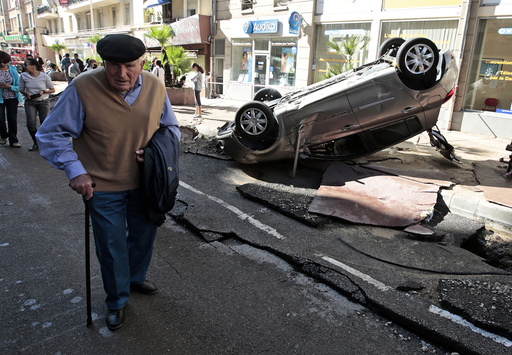 A man walks past an overturned car in the street that was damaged in flooding caused by torrential rain in Cannes