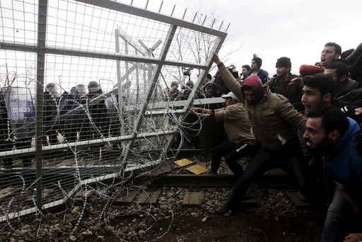 File photo of stranded refugees and migrants trying to bring down part of the border fence during a protest at the Greek-Macedonian border, near the Greek village of Idomeni
