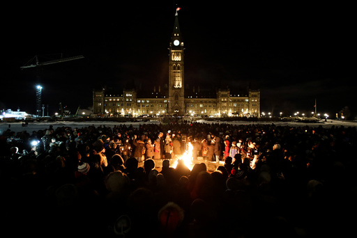 People gather around the Centennial Flame on Parliament Hill during a vigil following a deadly shooting at a Quebec City mosque, in Ottawa