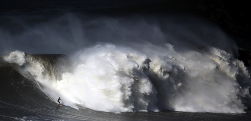 A surfer drops in on a large wave at Praia do Norte in Nazare