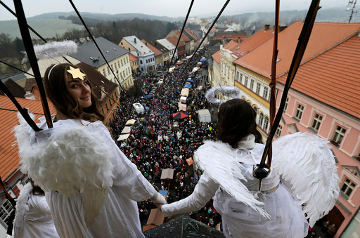 Women dressed as angels hold hands as they hang from a wire during a Christmas market in the town of Ustek