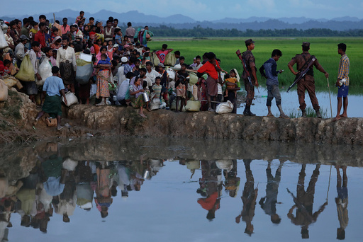 Rohingya refugees who fled from Myanmar wait in the rice field to be let through after after crossing the border in Palang Khali