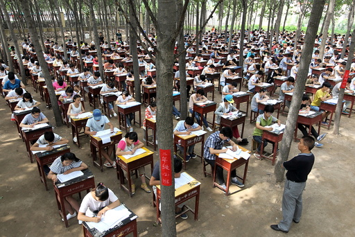 Students take term final exam among trees outside a classroom building at a middle school in Xinxiang