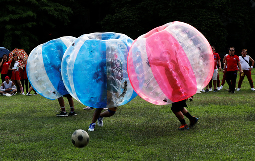 Employees of a company and their families play a friendly game of bubble bump soccer at the University of the Philippines school campus in Quezon city, Metro Manila