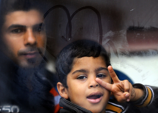 A migrant boy flashes a victory sign inside a bus at the Croatia-Slovenia border crossing at Bregana