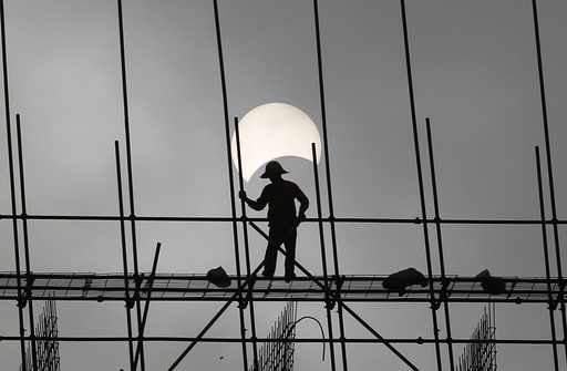 A partial solar eclipse is seen as a labourer works at a construction site in Phnom Penh, Cambodia