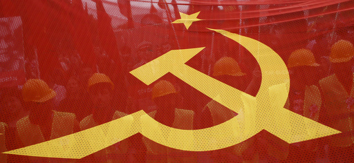 People walk behind a red banner with hammer and sickle symbols during a May Day rally in Istanbul