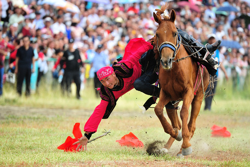 A man performs riding a horse during a traditional sports meeting in Barkol Kazakh Autonomous County