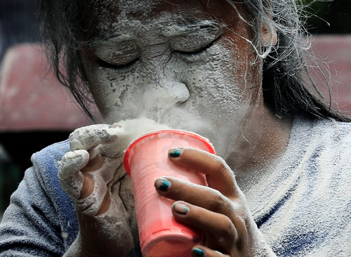 A girl's face is covered by a white powder after blowing on it, while participating in a game during a religious festival honouring patron saint Santa Rita de Cascia in Paranaque city