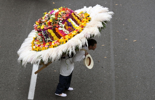 A man wearing a floral arrangement on his back takes part in the annual flower parade, in which flower growers known as 