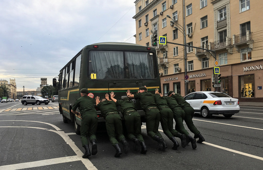 Russian servicemen push a bus along an avenue in Moscow