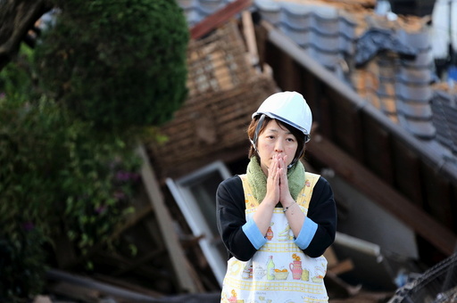 Woman reacts in front of collapsed house caused by an earthquake in Mashiki town