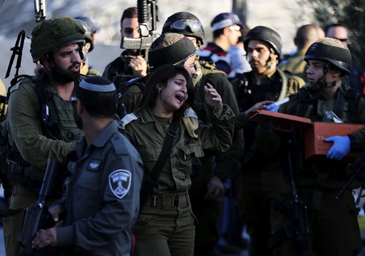 Israeli female soldier reacts at the scene where a Palestinian stabbed and killed an Israeli soldier at a petrol station before he was shot dead by soldiers near the West Bank village of Khirbit Al-Misbah