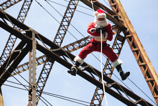 Guatemalan firefighter Chacon, wearing a Santa Claus outfit, rappels down the Belize bridge to give toys to children living under the bridge, in Guatemala City