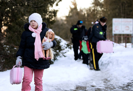 A young girl carries her doll and suitcase as her family that claimed to be from Turkey are met by Royal Canadian Mounted Police (RCMP) officers after they crossed the U.S.-Canada border illegally leading into Hemmingford, Quebec Canada