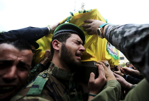 A Lebanon's Hezbollah member reacts as he carries with others the coffin of his comrade, Mohamad Sfawi, who was killed fighting alongside Syrian army forces in Syria, during his funeral in Qnarit village, southern Lebanon