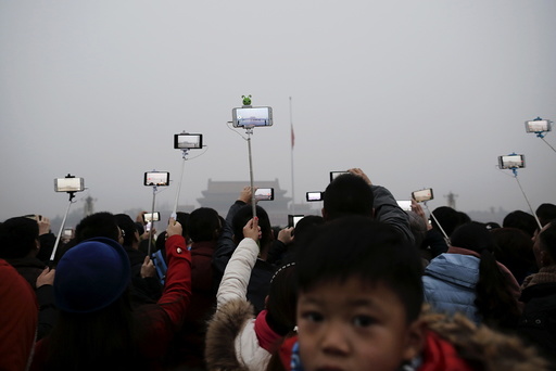 People film with their cameras during a flag-raising ceremony amid heavy smog at the Tiananmen Square, after the city issued its first ever 
