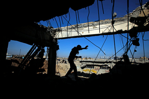 An Iraqi runs through a destroyed building as Iraqi forces battle with Islamic State militants, in western Mosul