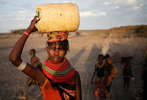 A woman carries a water canister in a village near Loiyangalani
