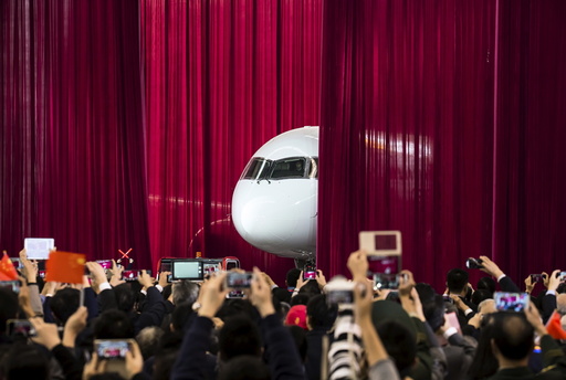 People take pictures and videos as the first C919 passenger jet is pulled out from behind a curtain during a news conference in Shanghai