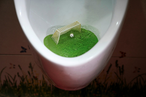 An urinal filter designed in the likeness of a soccer field with a goal post and a ball is pictured in a men's room of a public toilet in Shanghai