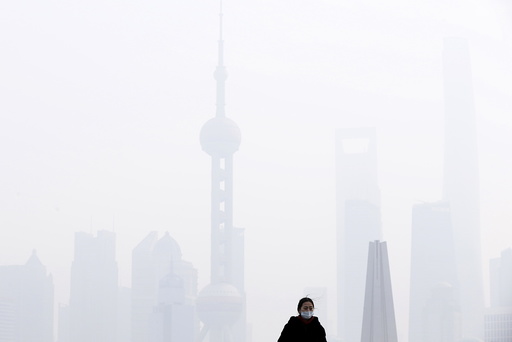 A woman wearing a face mask stands in front of financial district of Pudong amid heavy smog in Shanghai