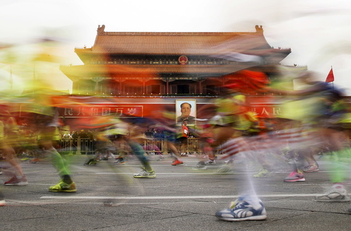 Participants run past the Tiananmen gate, with a portrait of China's late leader Mao hanging on it, during the Beijing International Marathon in Beijing