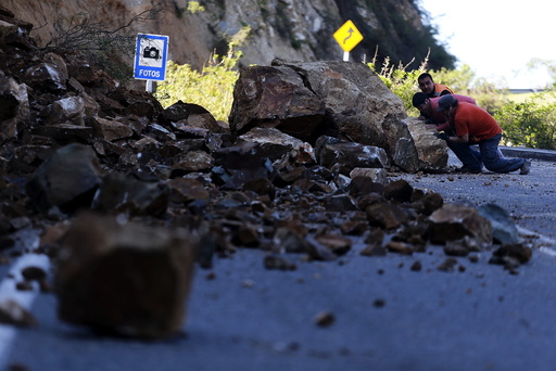 Workers try to remove a rock on the road to Illapel town after an earthquake hit areas of central Chile