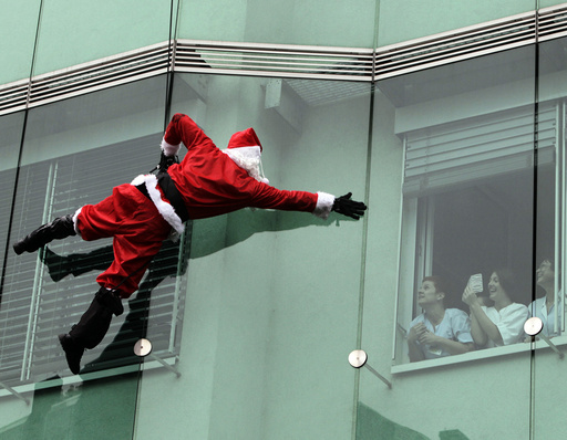 A member of the special police forces dressed in a Santa Claus suit waves to staff as he descends from the roof of a pediatrics clinic in Ljubljana